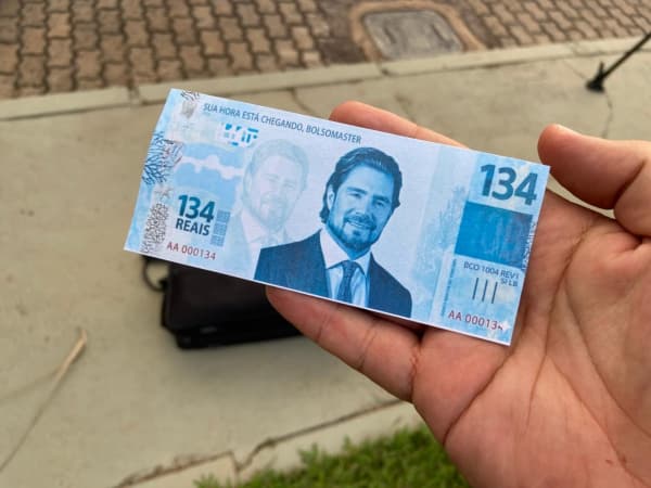 Protesto na casa de Flávio tem marcha fúnebre e ‘chuva’ de nota de R$ 134; veja vídeo